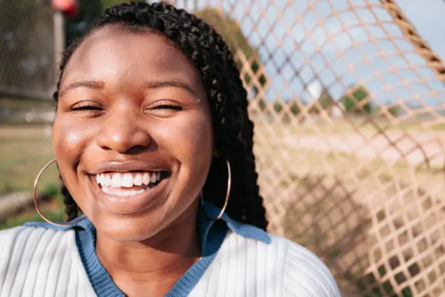 Young woman laughing outdoors with a bright smile
