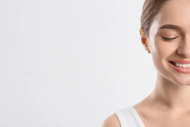 Close-up of a woman smiling against a light background
